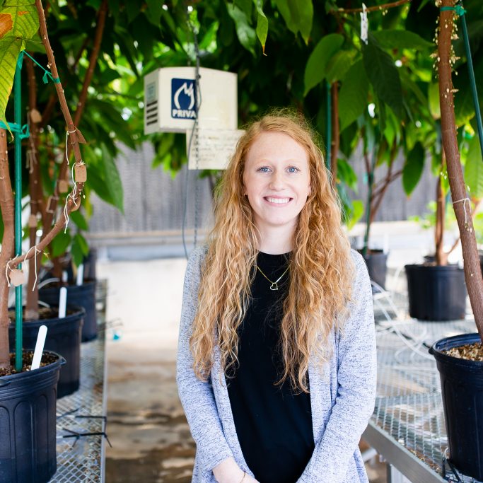 student standing in a greenhouse